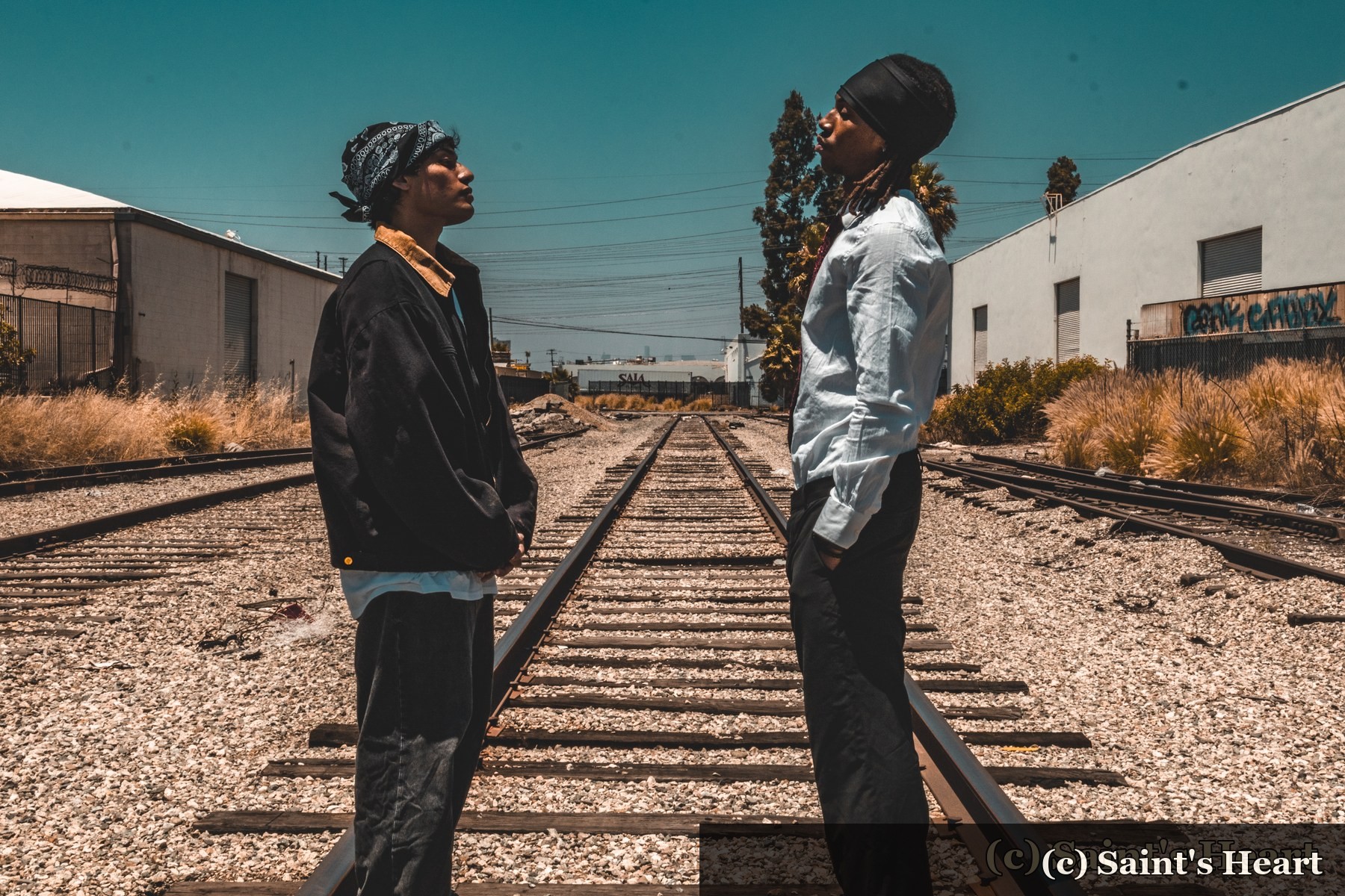Two people facing each other on railway tracks